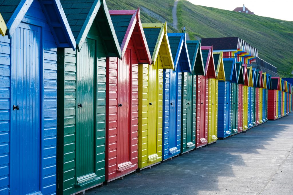 Row of beach huts in bright primary colours to illustrate the use of protective topcoat paint