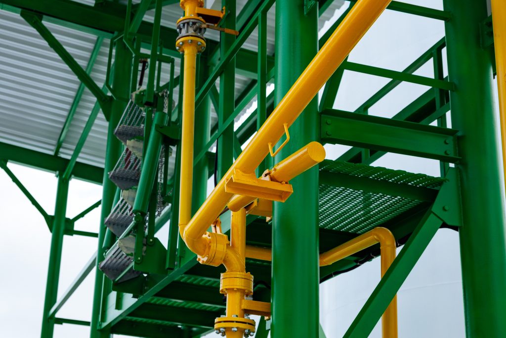 Metal industrial walkway and pipework painted in gloss green and yellow paint to illustrate the use of protective paint topcoat.