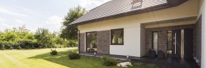 Bungalow with grey doors and window frames and lawn in sunshine