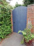 Grey painted gate in red brick wall with green planting