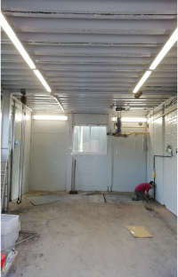 Decorator painting wall of brightly lit warehouse white
